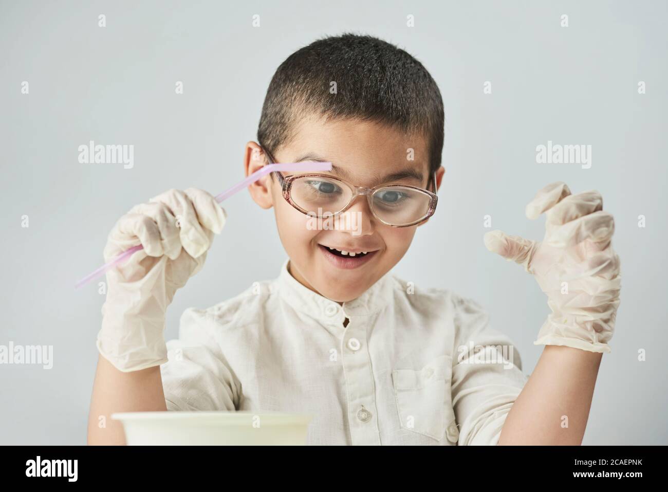 Funny kid making experiments at the workshop and exploring the world of chemistry against the white background Stock Photo