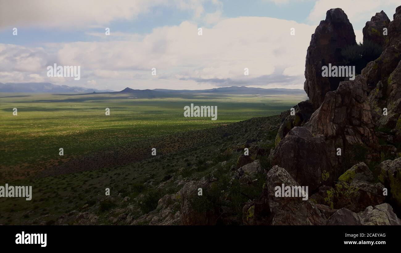 A view from a rocky mountain, showing the vast green plains of rural Mongolia Stock Photo