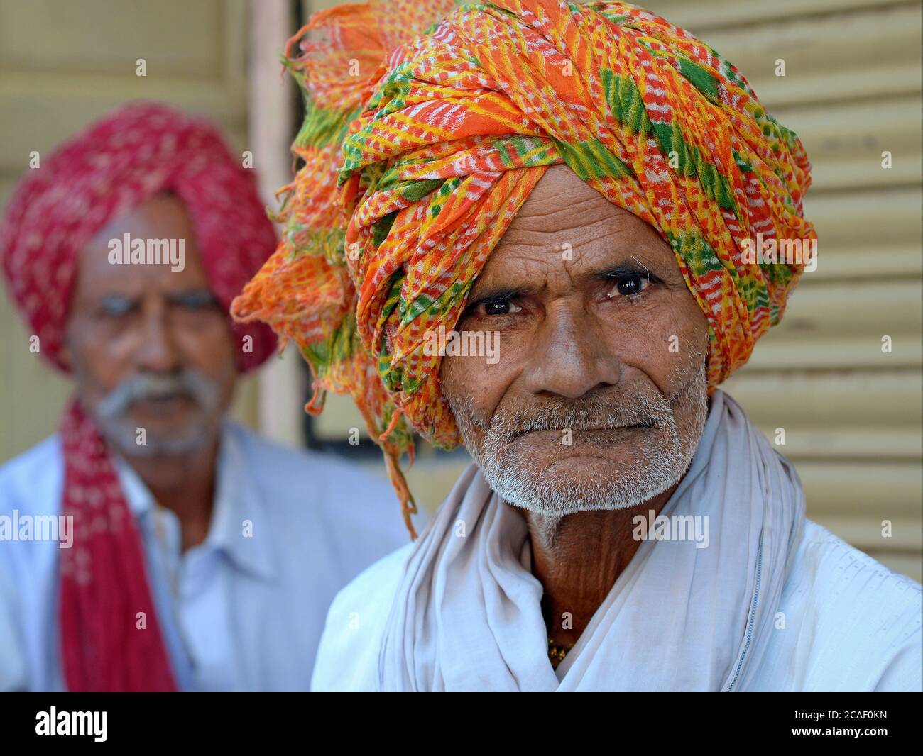 Two elderly Indian Rajasthani peasants with colourful Rajasthani turbans (pagari) look at the camera and pose for a photo. Stock Photo