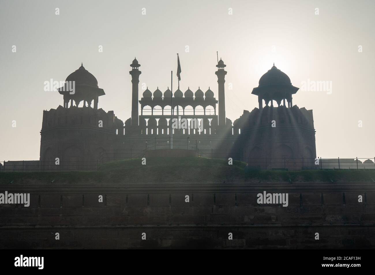 the sun shining from behind a domed tower at red fort in old delhi Stock Photo