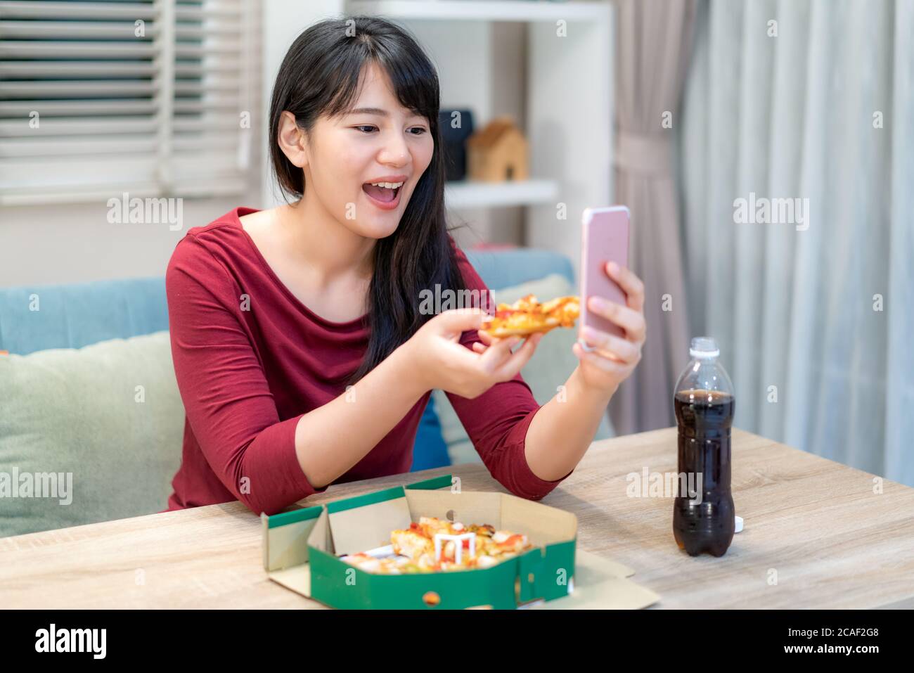 Asian woman virtual happy hour meeting dinner and eating pizza food online together with her boyfriend in video conference with digital tablet for a o Stock Photo