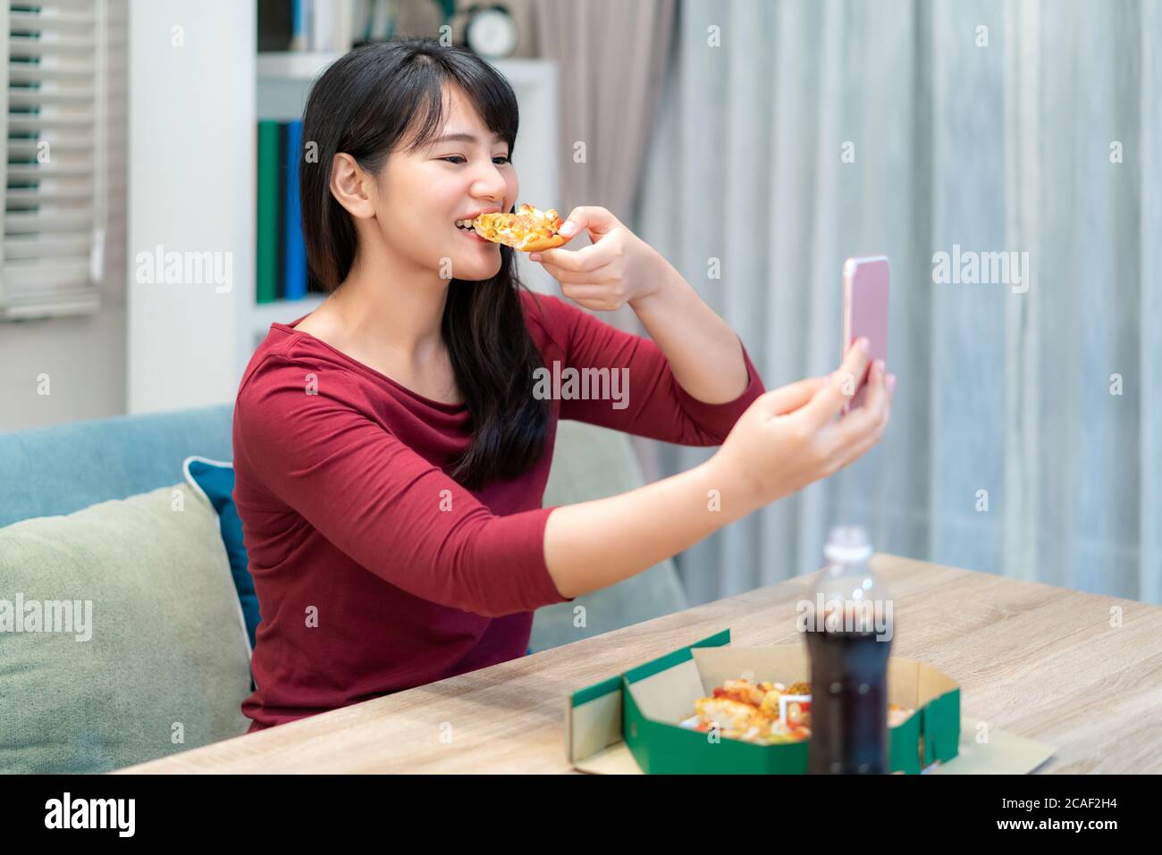 Asian woman virtual happy hour meeting dinner and eating pizza food online together with her boyfriend in video conference with digital tablet for a o Stock Photo