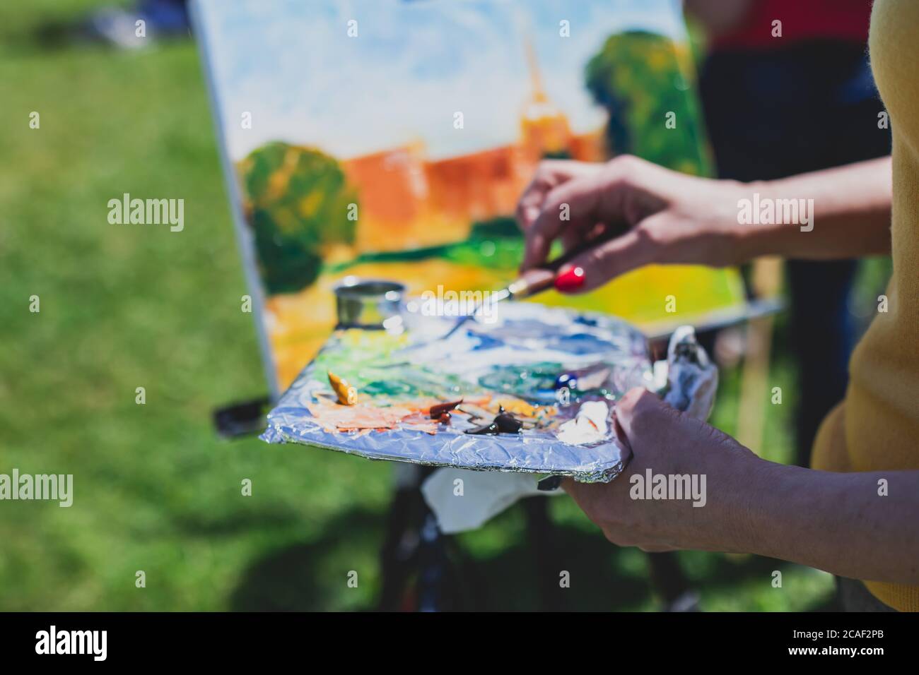 Process of plein air painting, group class of adult talented students in the park with paints easels, and canvases during lesson of watercolour painti Stock Photo