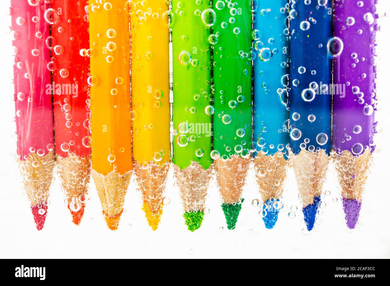 Colorful pencils in water with bubbles on white background Stock Photo