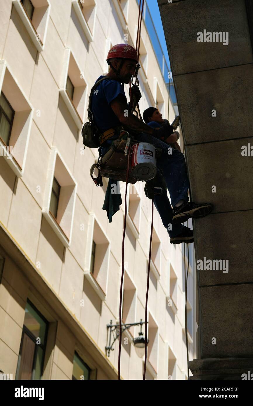 Two vertical workers employed by Solver Soluciones Verticales hanging on climbing ropes renovating a facade or building exterior in Granada, Spain. Stock Photo