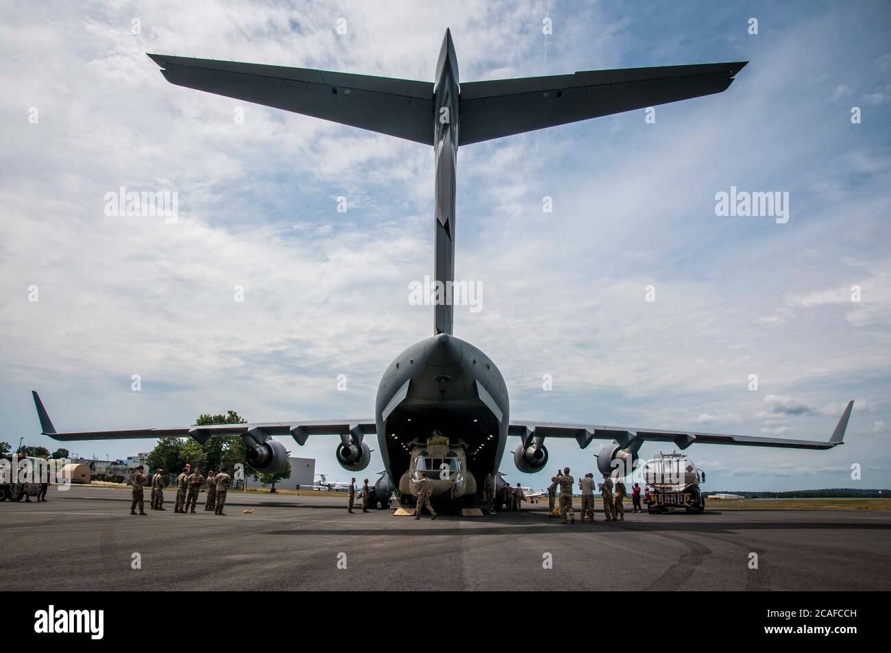 Soldiers assigned to the Connecticut National Guard unload a CH-47 Chinook helicopter belonging to 2nd Battalion, 104th Aviation Regiment from an Alaska National Guard C-17 Globemaster at the Army Aviation Support Facility in Windsor Locks, Conn. Aug. 6, 2020. The 2-104th recently completed an extended deployment to Afghanistan in support of Operation Freedom Sentinel. Stock Photo