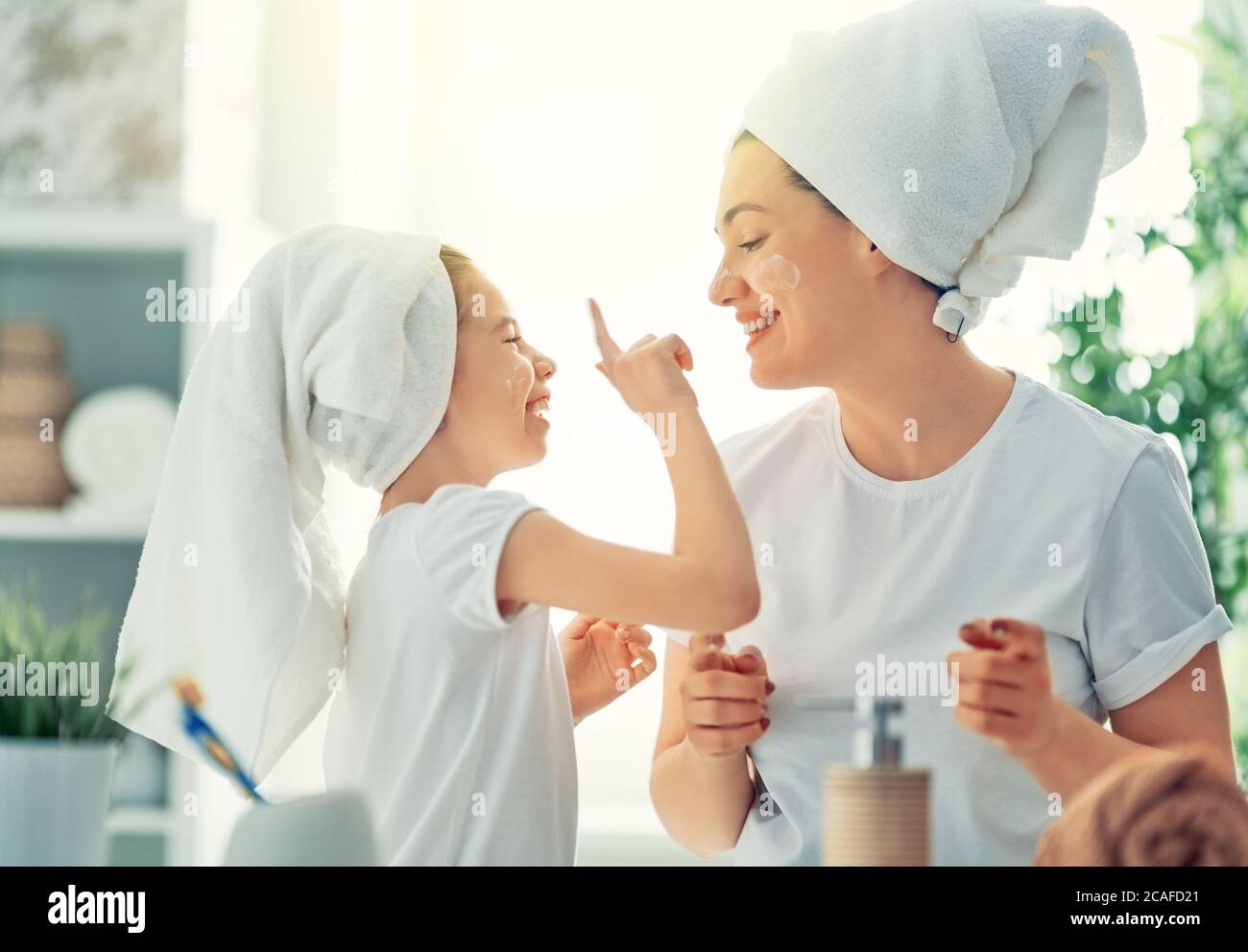 Happy family! Mother and daughter child girl are caring for skin in the