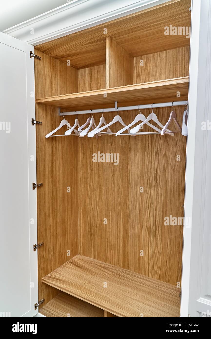 Opened white wardrobe with wooden drawers and shelves. Wooden filling of  wardrobe and white clothes hangers. Wooden wardrobe with white lacquered  cabi Stock Photo - Alamy