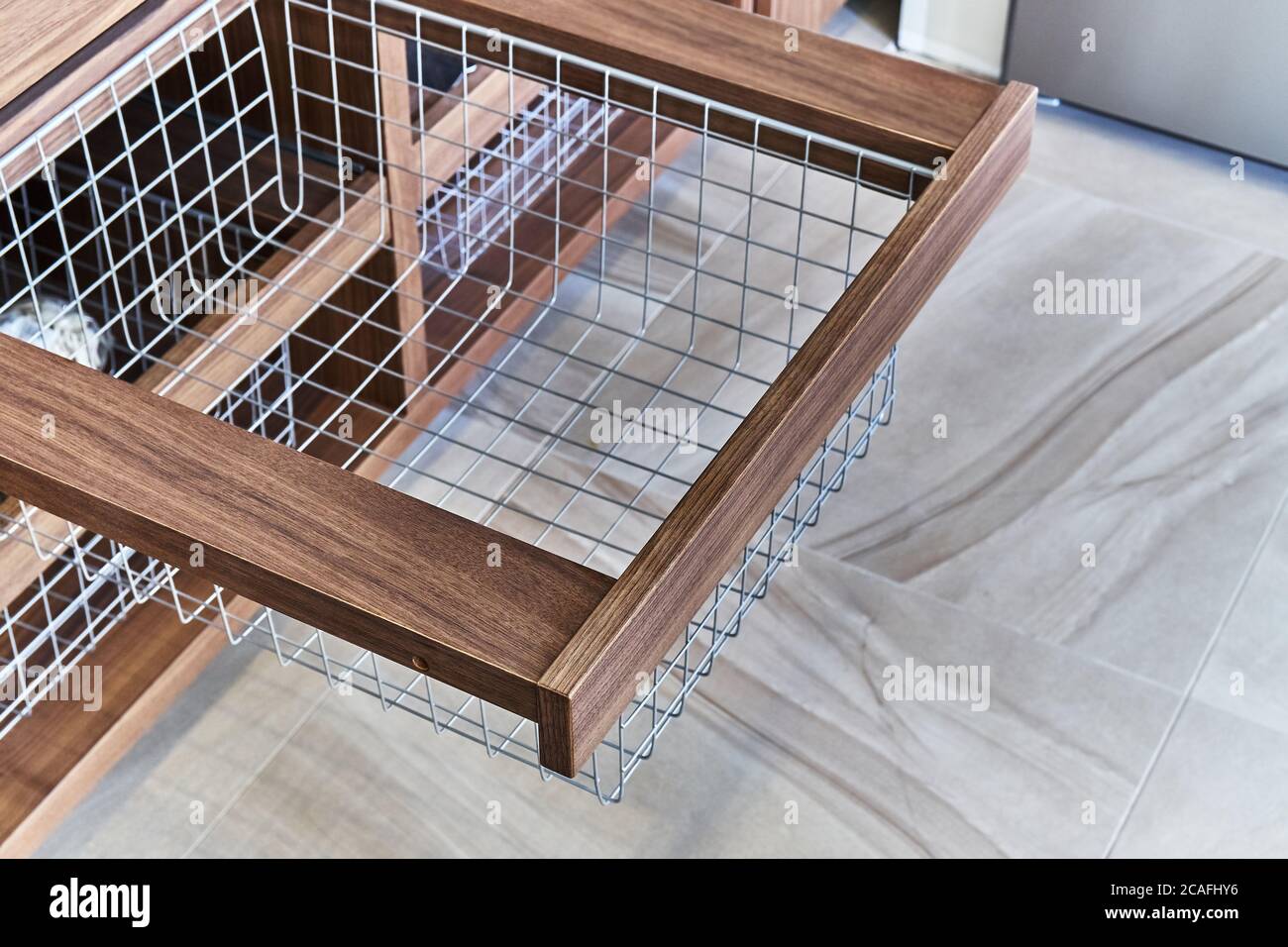 Storage organization. Metal mesh basket in wooden drawer in food storage room. Close-up Stock Photo