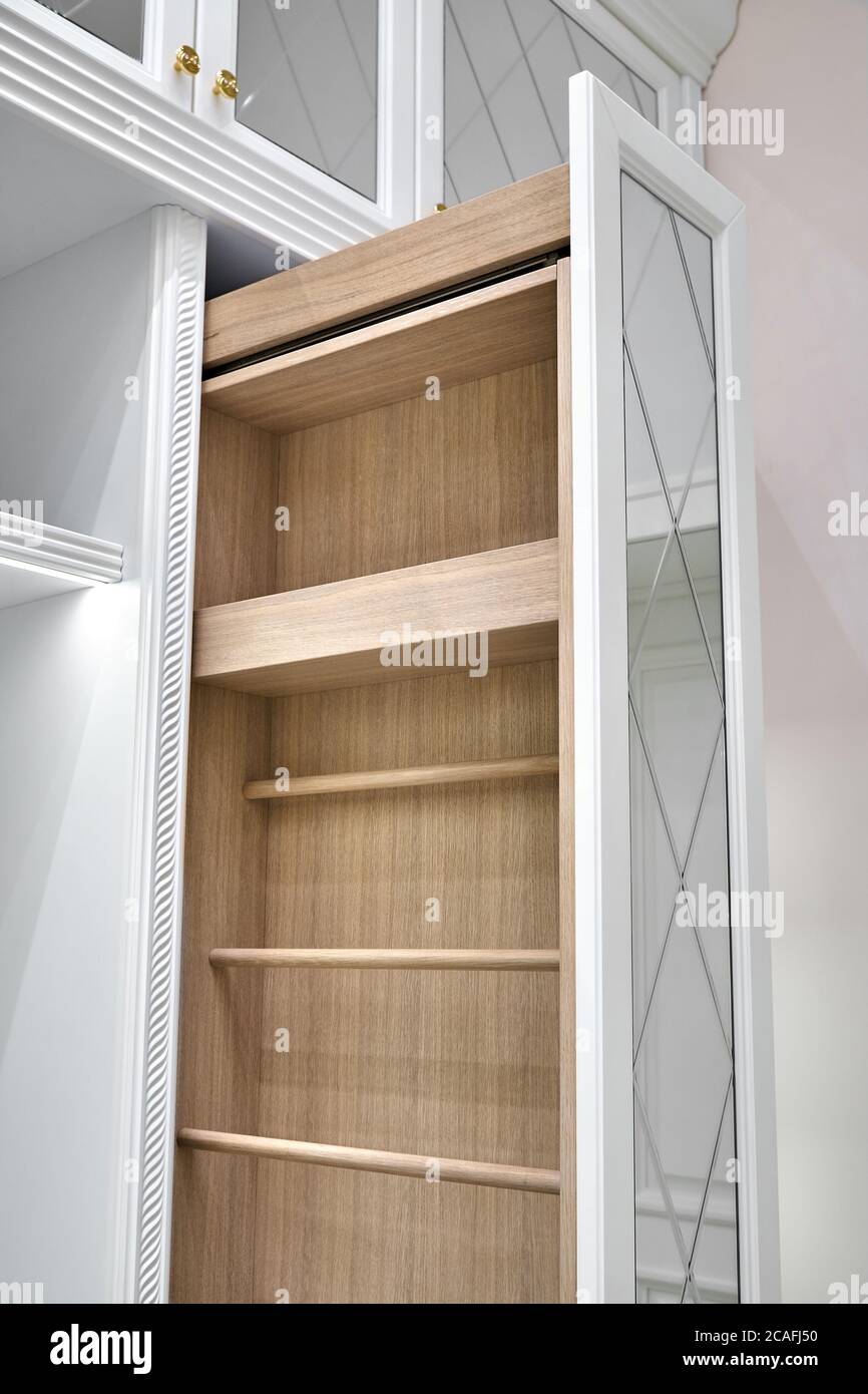White wardrobe with mirror doors. Vertical pull-out wooden cabinet in the dressing room. Classic furniture close-up Stock Photo
