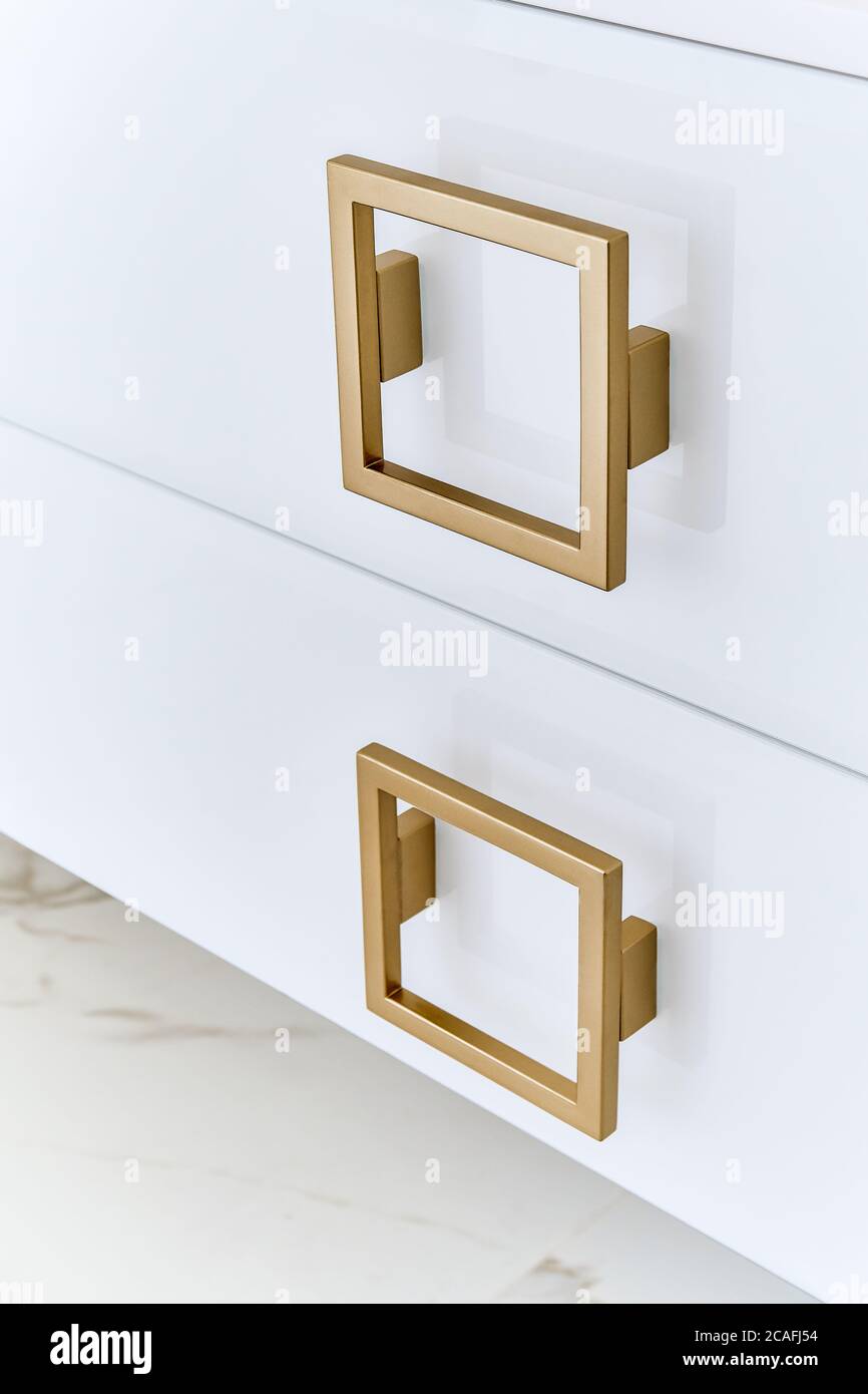 Square gold handles on a gloss doors of bathroom vanity. Close