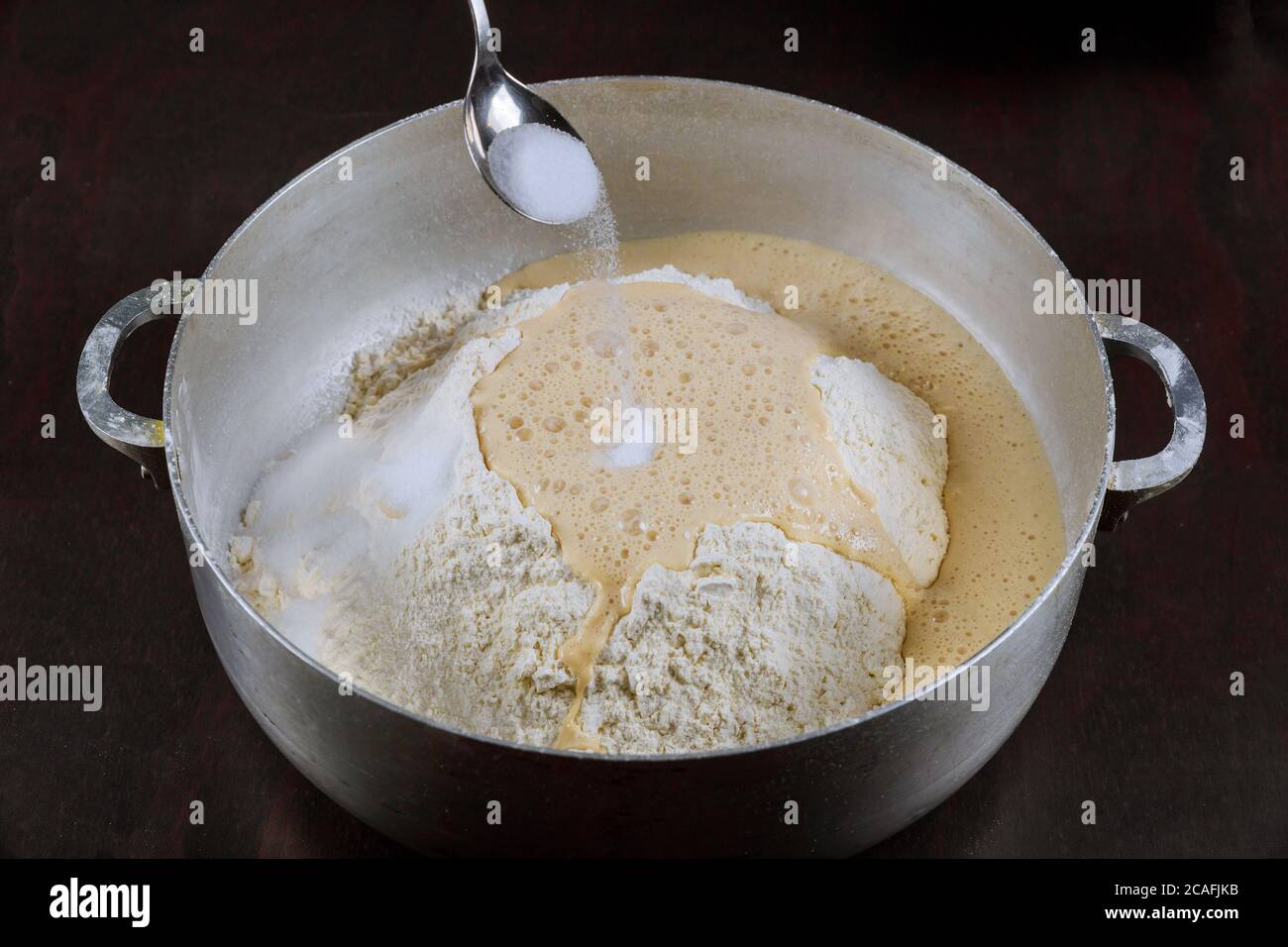 Adding salt to yeast dough for making homemade bread. Stock Photo