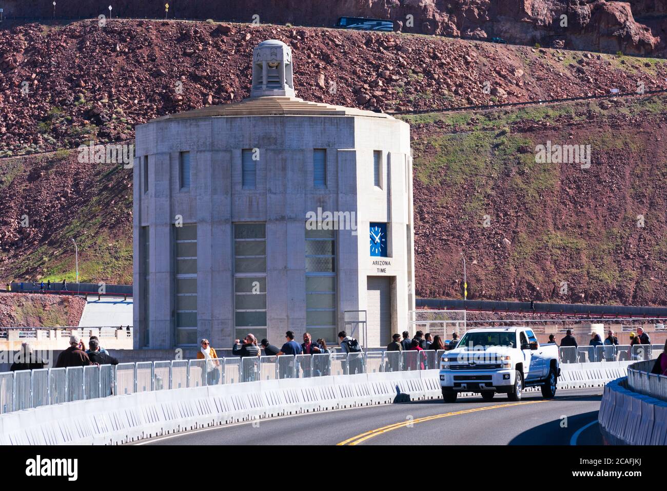 Tourists, visitors and automobile traffic at the top of Hoover Dam. Water intake tower on Arizona side with clock showing Arizona time - Boulder City, Stock Photo
