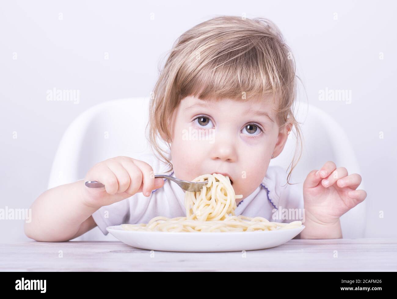 Beautiful girl eating and playing with spaghetti and fork Stock Photo