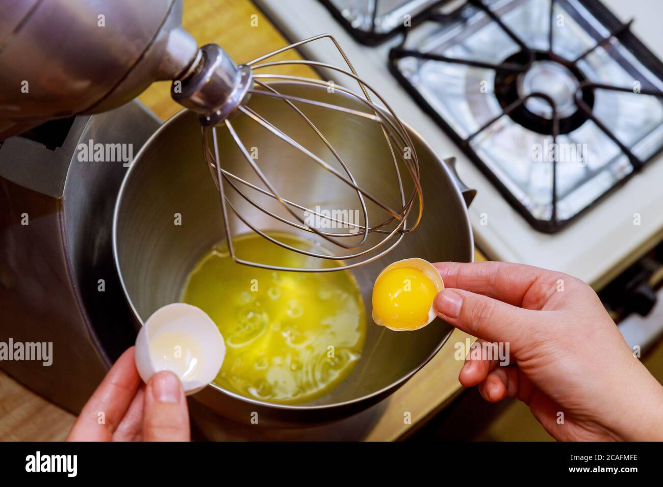 A woman separates egg white from egg yolk to make a sponge cake. Stock Photo