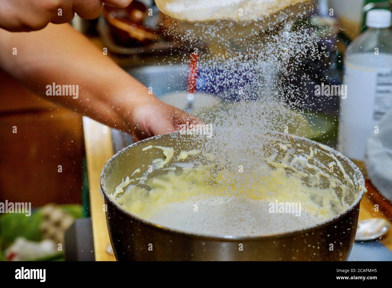 Woman sifts the flour in mixer bowl with dough. Making cake dough. Stock Photo