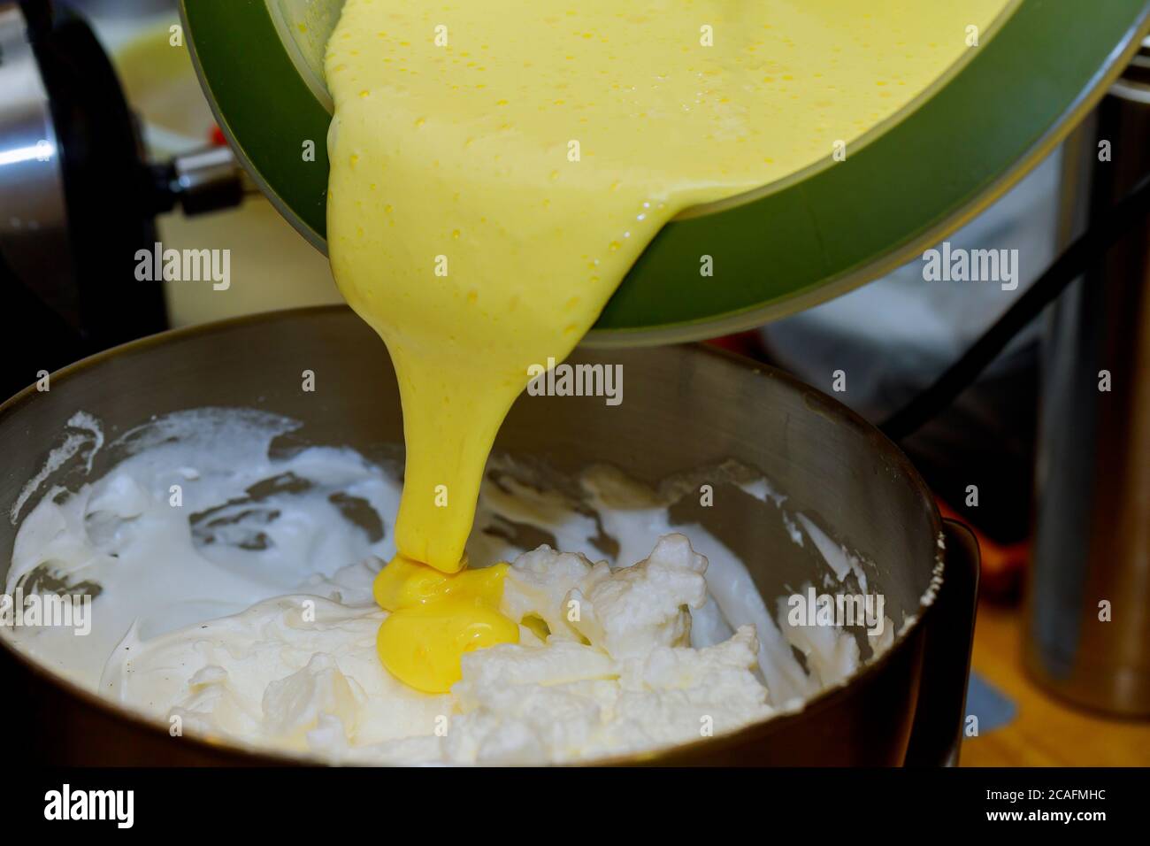 Adding whipped egg yolks in whipped egg white with sugar Stock Photo Alamy