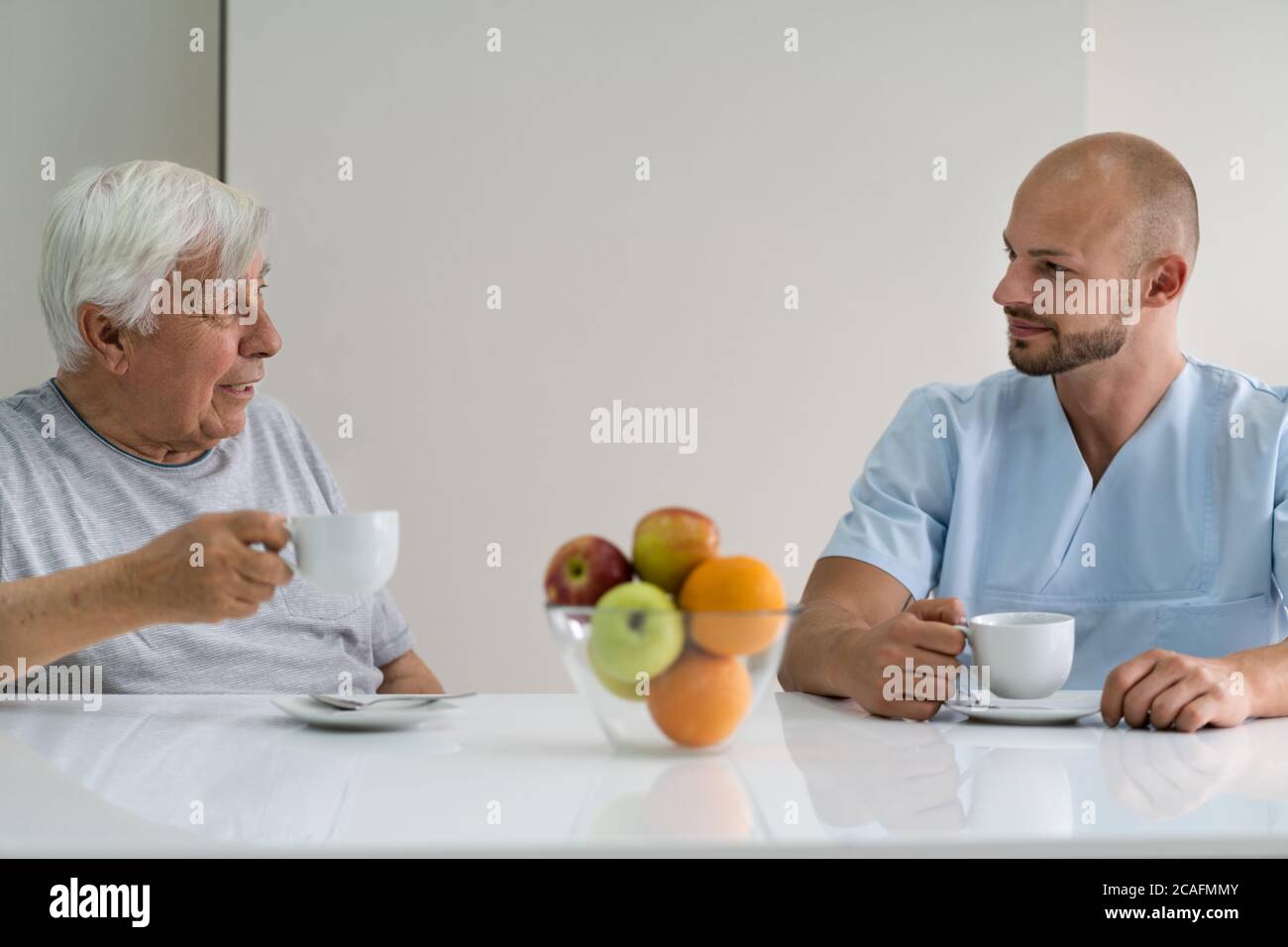 Caretaker In Retirement Home With Elder Man Stock Photo