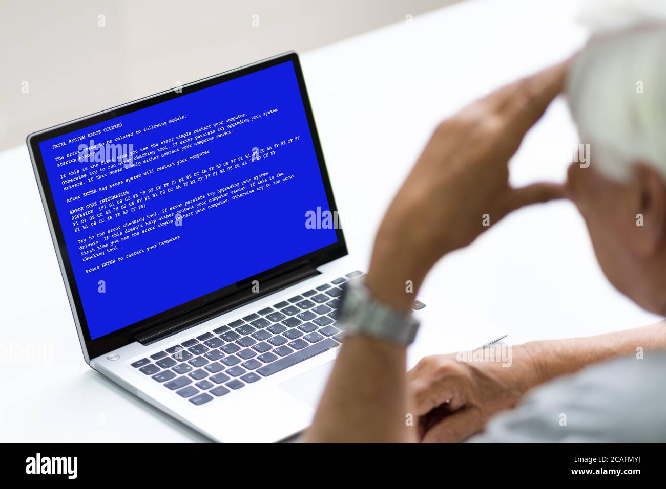 Senior With BSOD Death Screen On On On Hacked Laptop Stock Photo