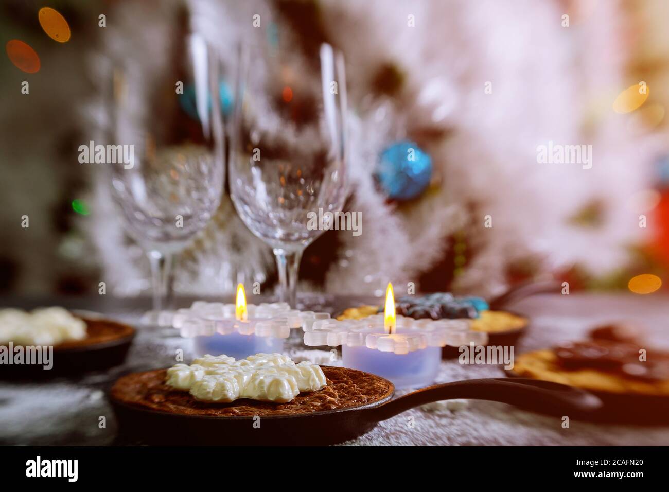 Burning candles on the dinning table with food, decorated Christmas tree. Christmas night. Stock Photo