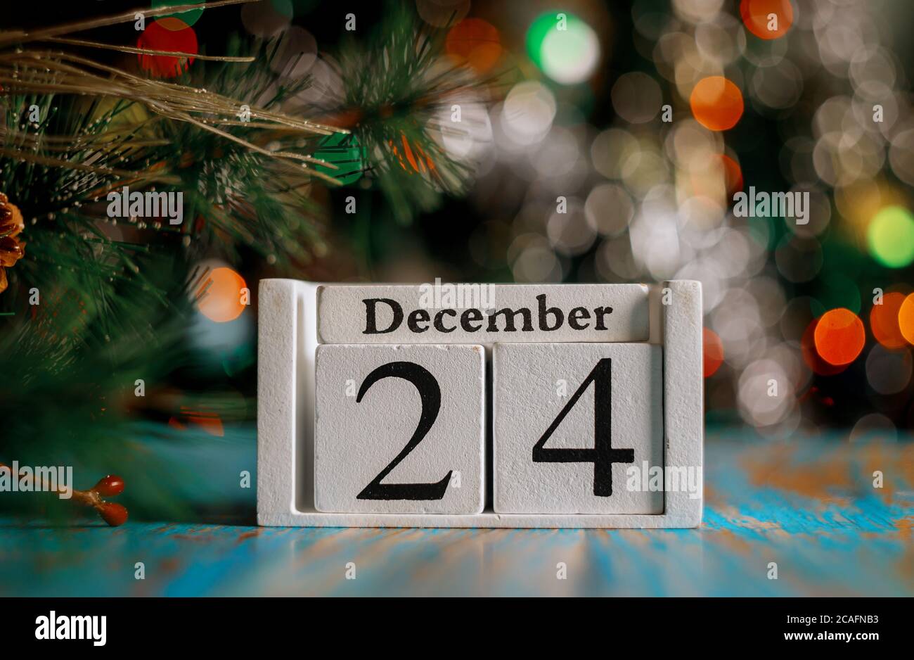 December 24 th on wooden calendar cube with christmas tree lights