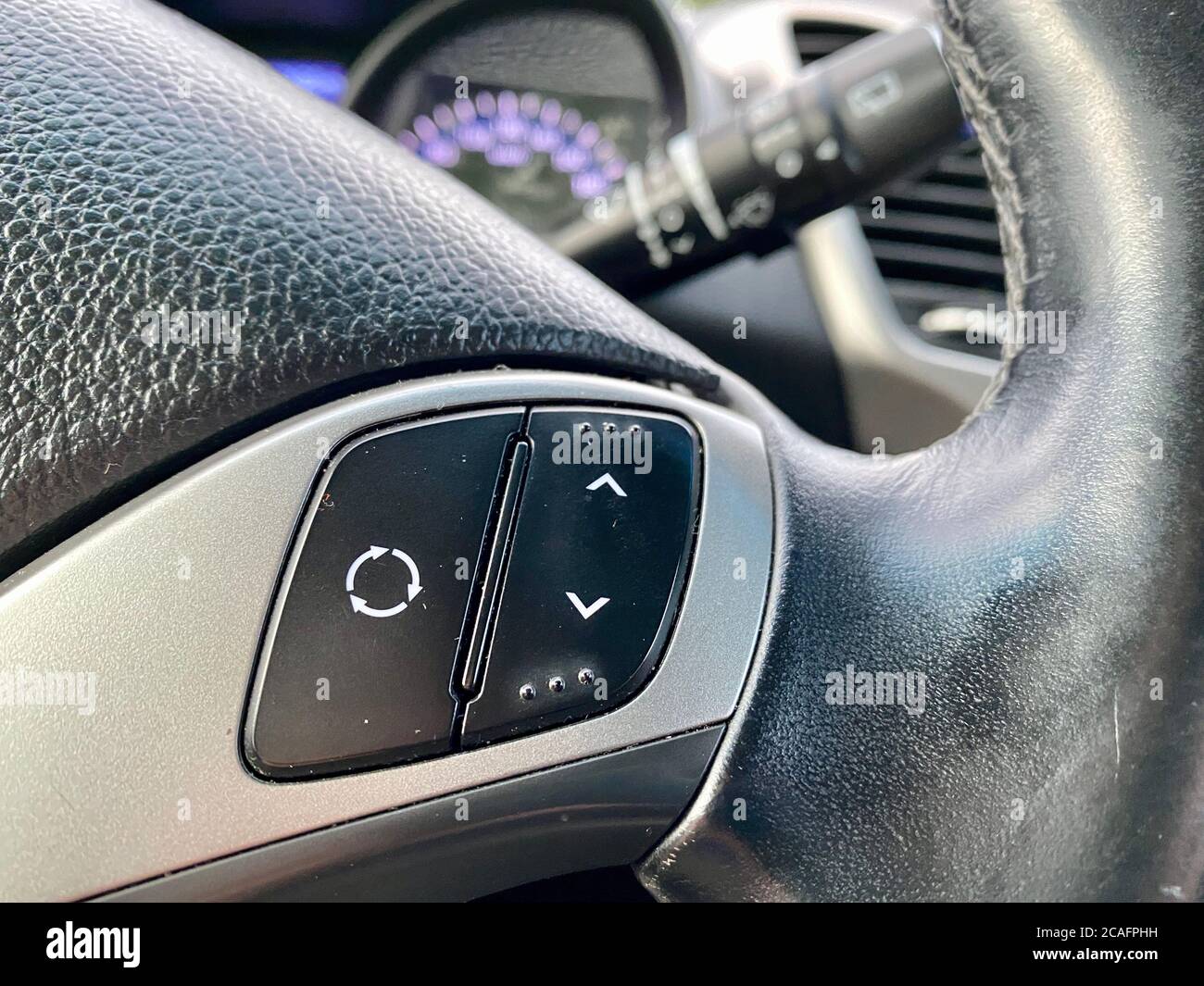 Modern black steering wheel with multifunction buttons for quick control, close-up in the car. Stock Photo