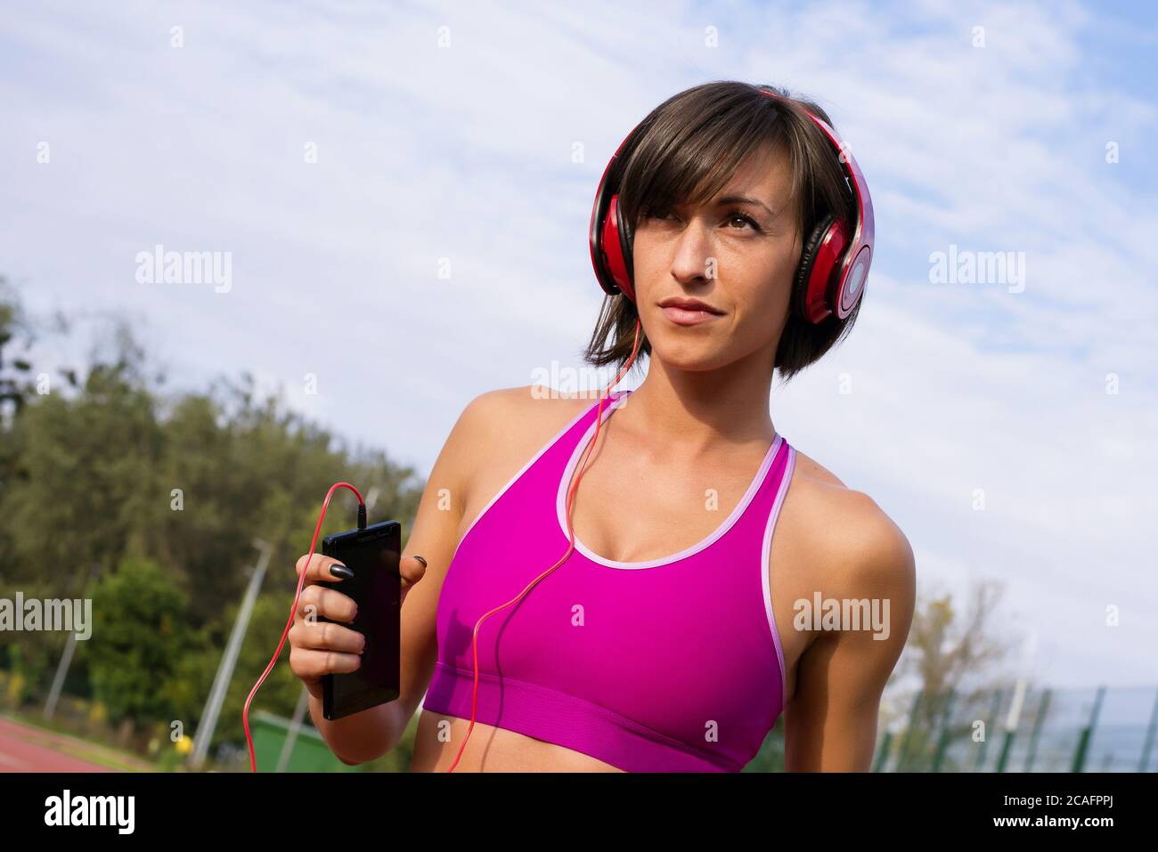 Sporty girl running and listening to music on background of sky Stock ...