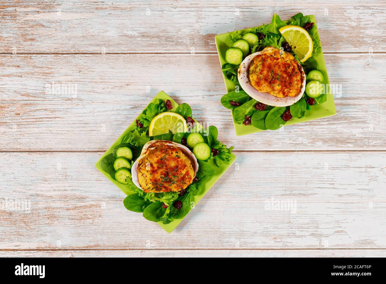 Seafood dish with stuffed clams and fresh salad on wooden background. Stock Photo