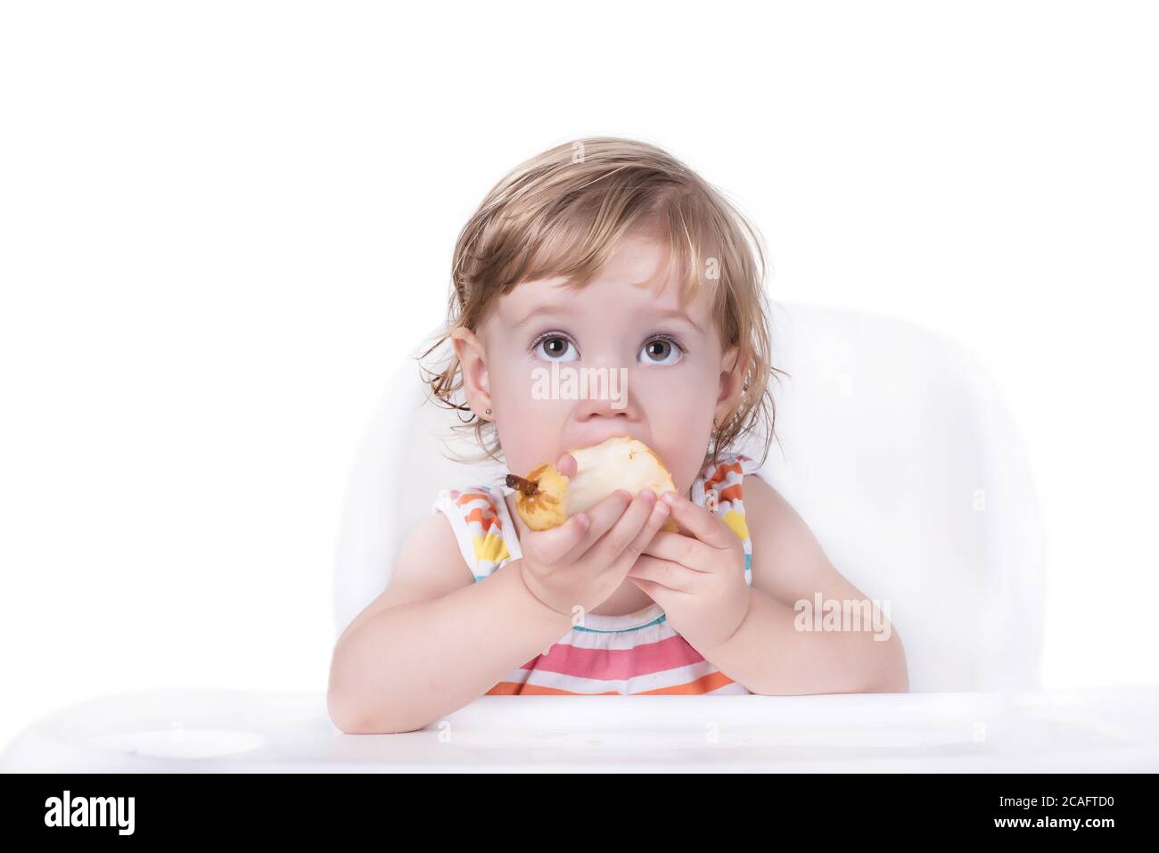 Selective focus shot of a happy little girl eating an apple Stock Photo