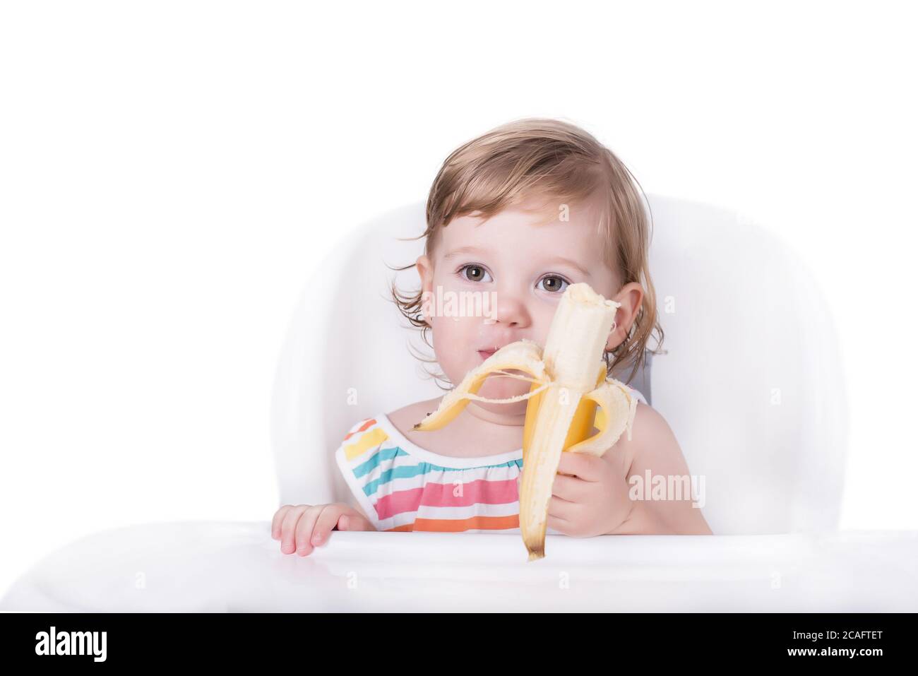 Selective focus shot of a happy little girl eating a banana Stock Photo