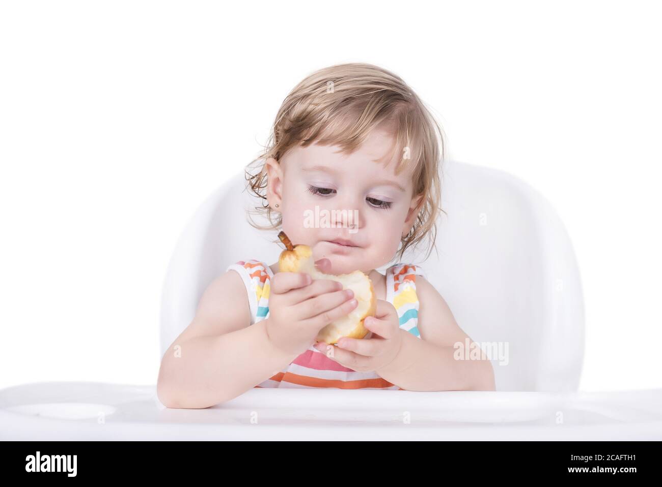 Selective focus shot of a happy little girl eating a pear Stock Photo