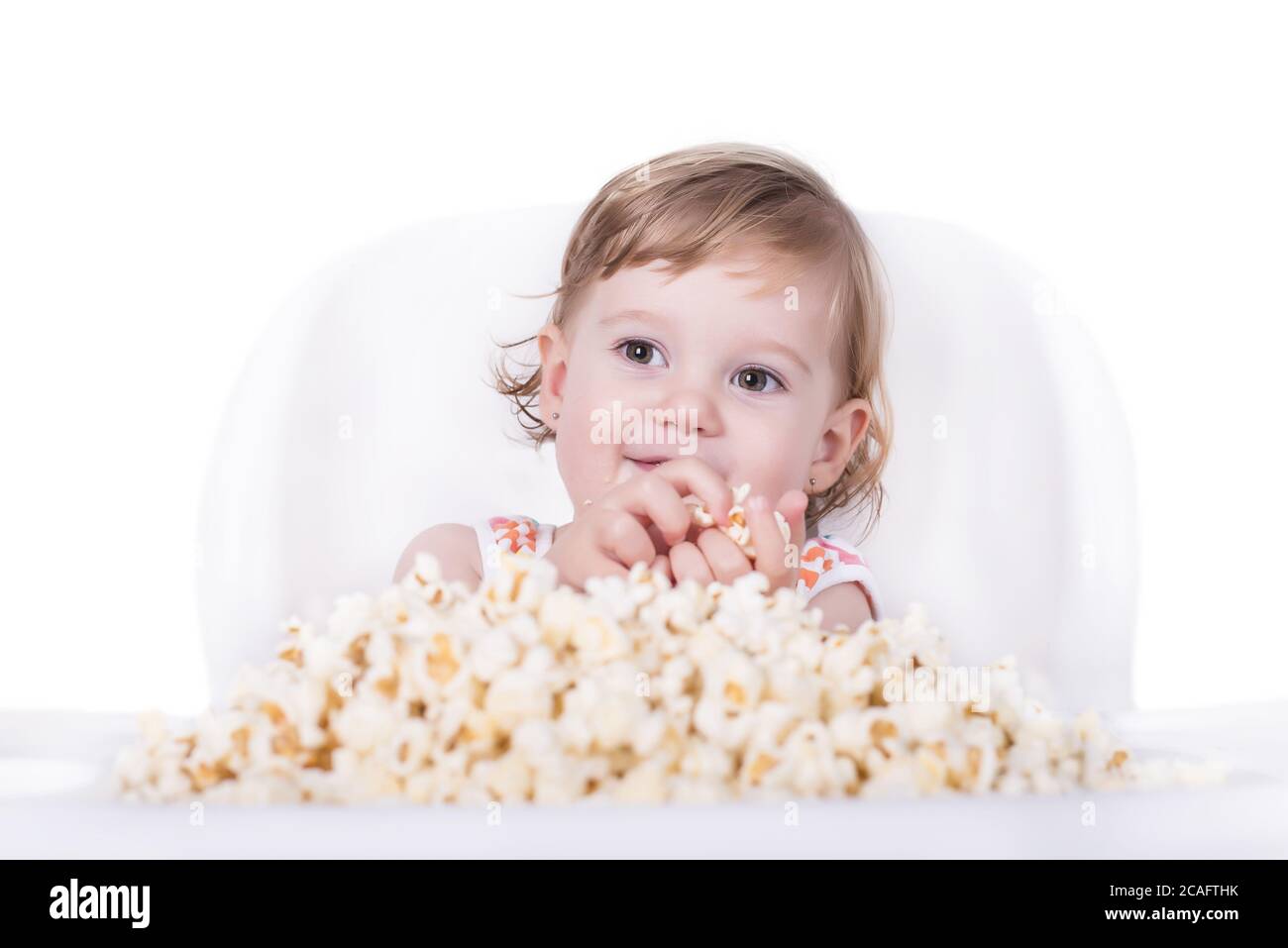 Selective focus shot of a happy little girl eating popcorn Stock Photo