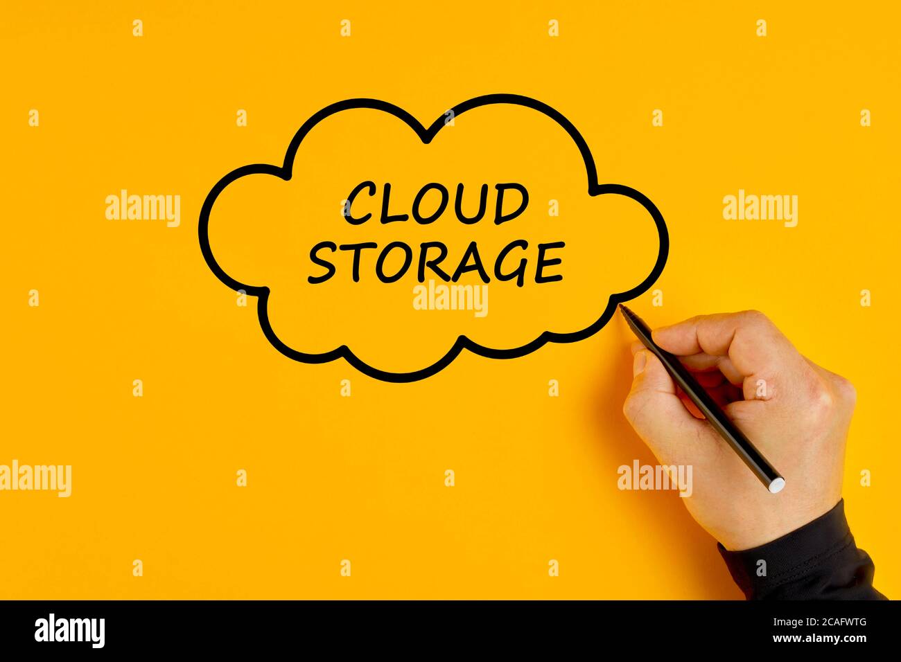 Male hand drawing a cloud with the words cloud storage written in it. Concept of digital data storage. Stock Photo