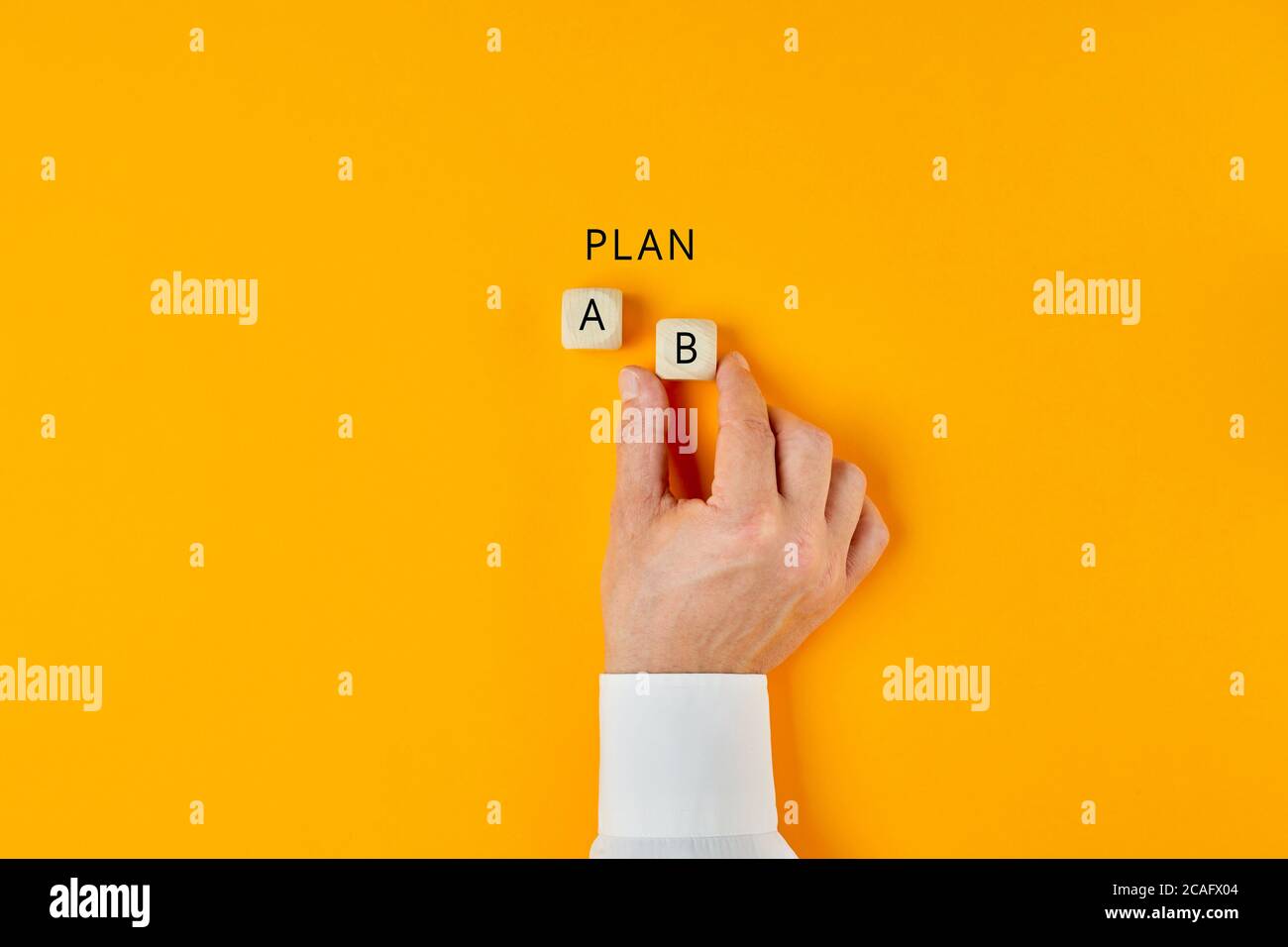 Hand of a businessman choosing business plan b out of two options on yellow background. Business strategy and decisions concept. Stock Photo