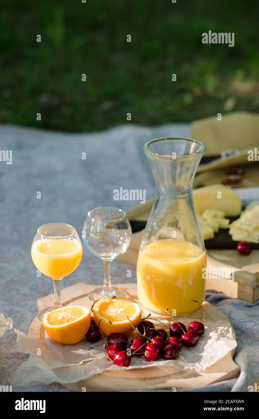 Blanket with food prepared for summer picnic at the park. Cheese, fruits, breads, juice and snacks on blanket Stock Photo