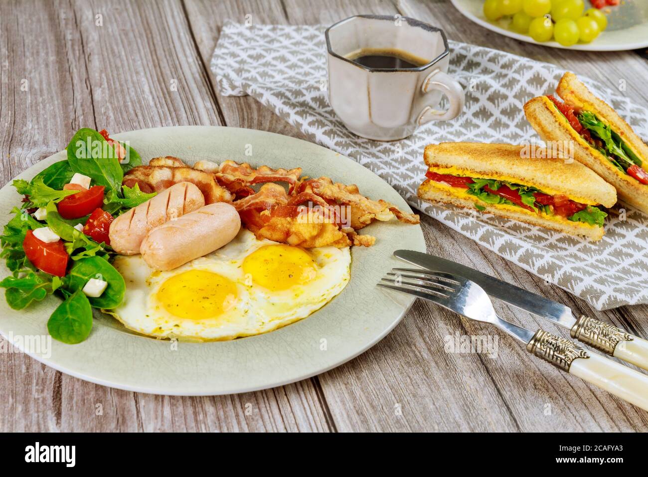 Traditional English breakfast with bacon, eggs, sausages, salad and