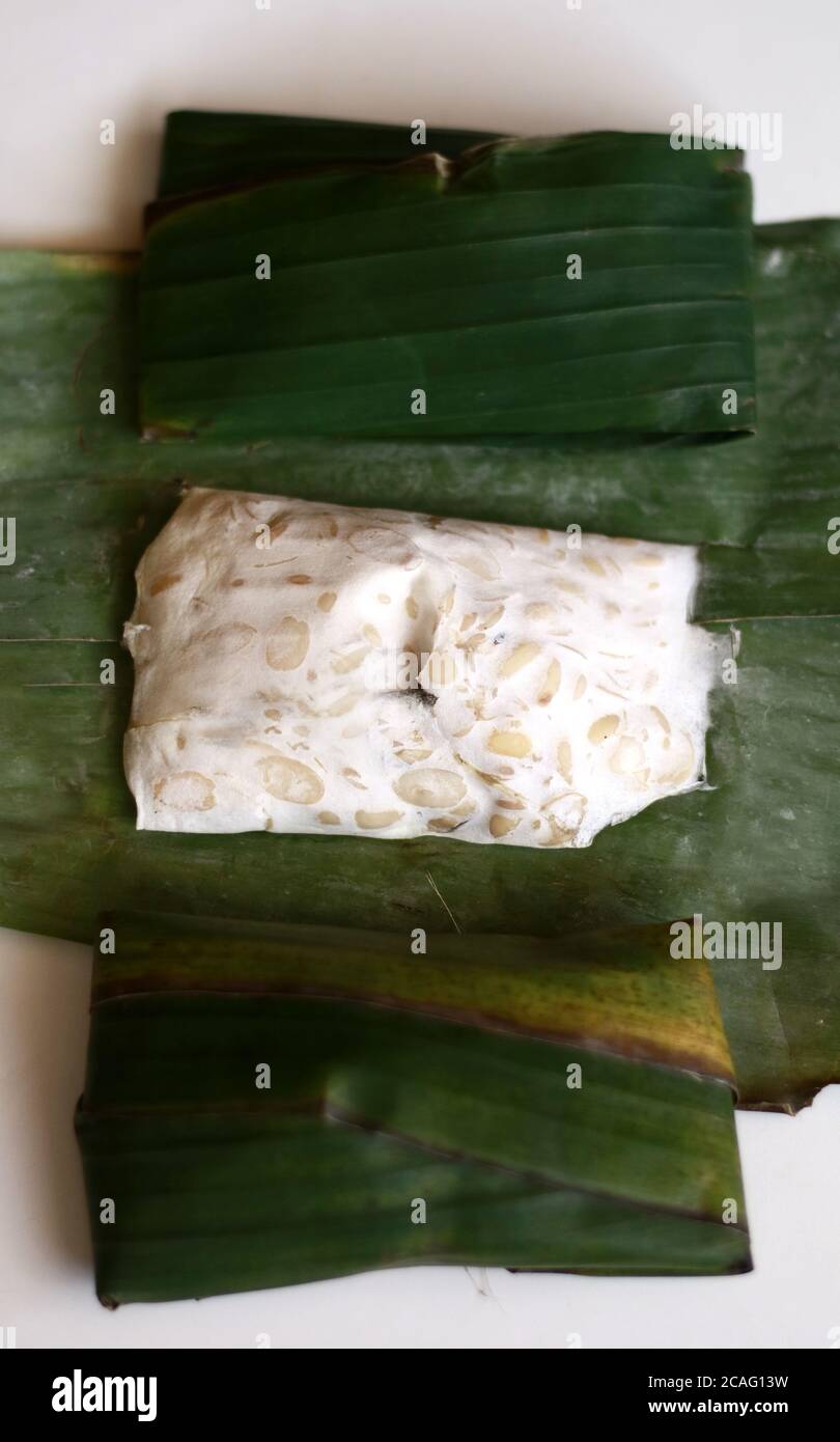 Tempeh on banana leaf, white background. Tempeh is a traditional soy