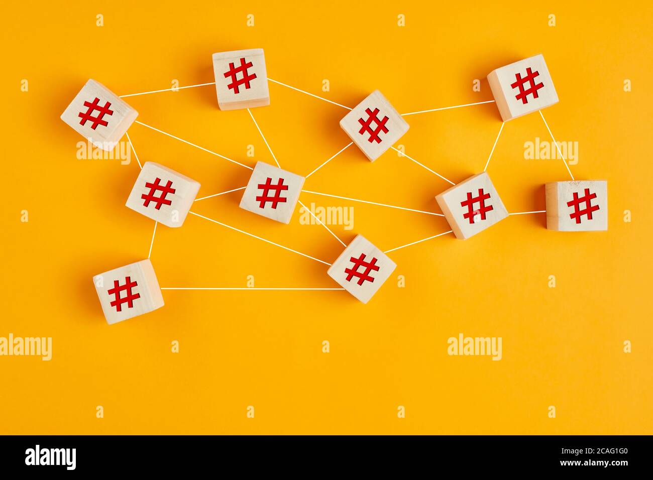 Hashtag symbols on wooden cubes connected to each other with lines on yellow background. Hashtag connection, search or trending topic in social media Stock Photo