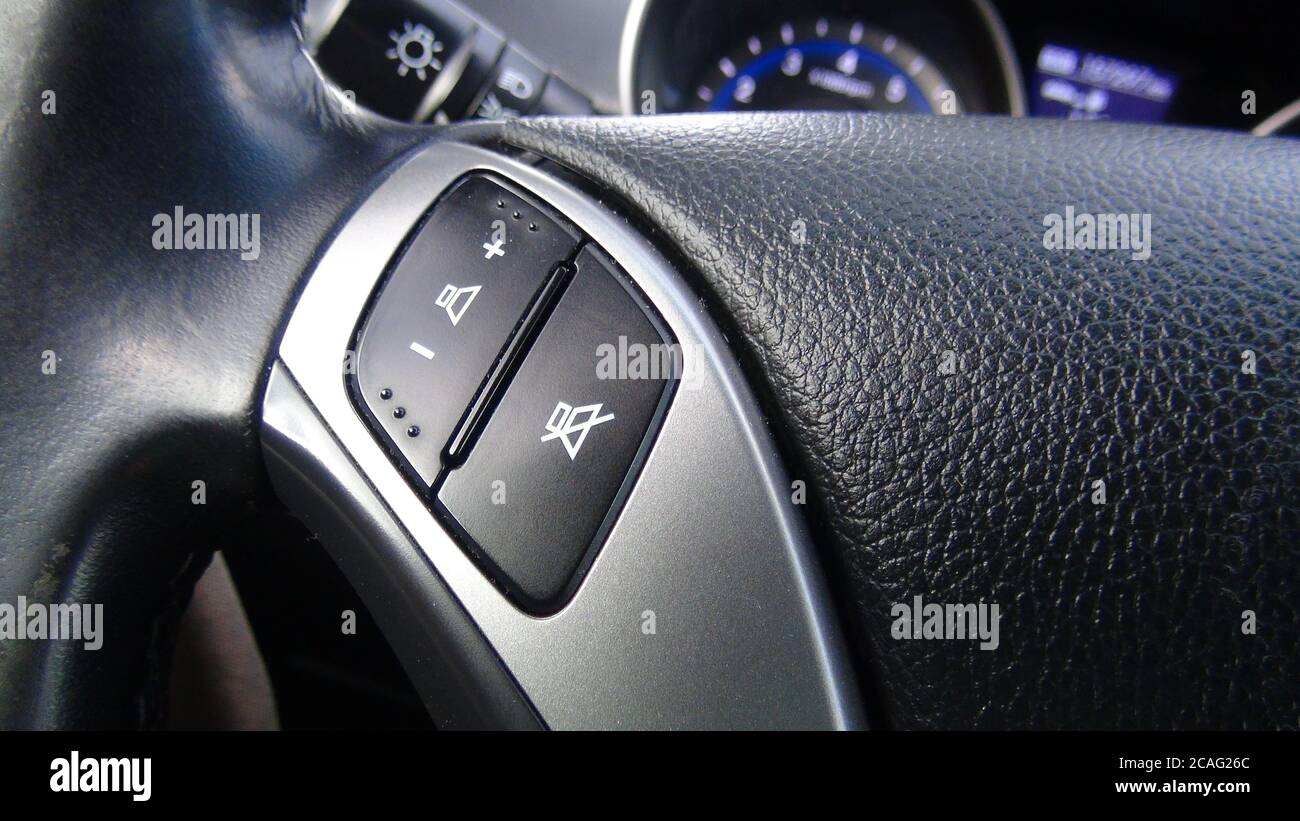 Modern black steering wheel with multifunction buttons for quick control, close-up in the car. Stock Photo