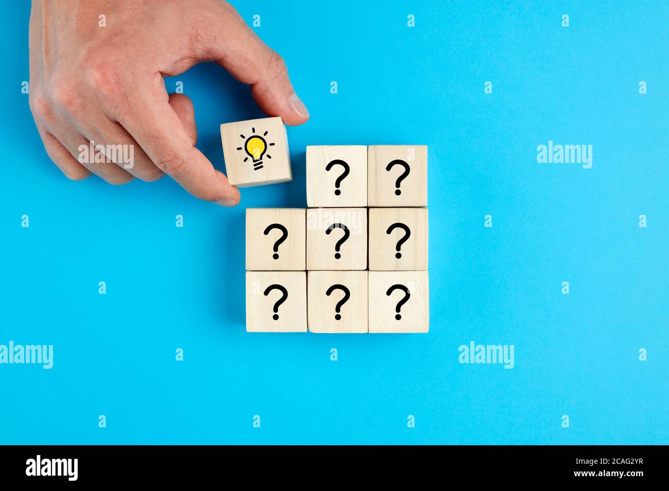 Concept of  problem solving, creativity, idea or innovation. Male hand places a wooden cube with hand drawn light bulb next to the cubes with question Stock Photo