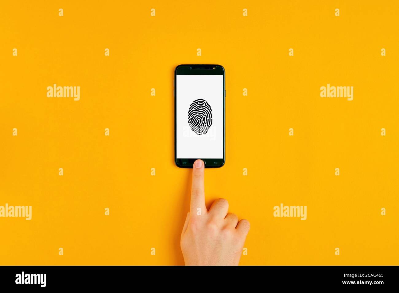 Male hand pressing the smartphone button with fingerprint scan icon on the sceen. Flat lay view. Stock Photo