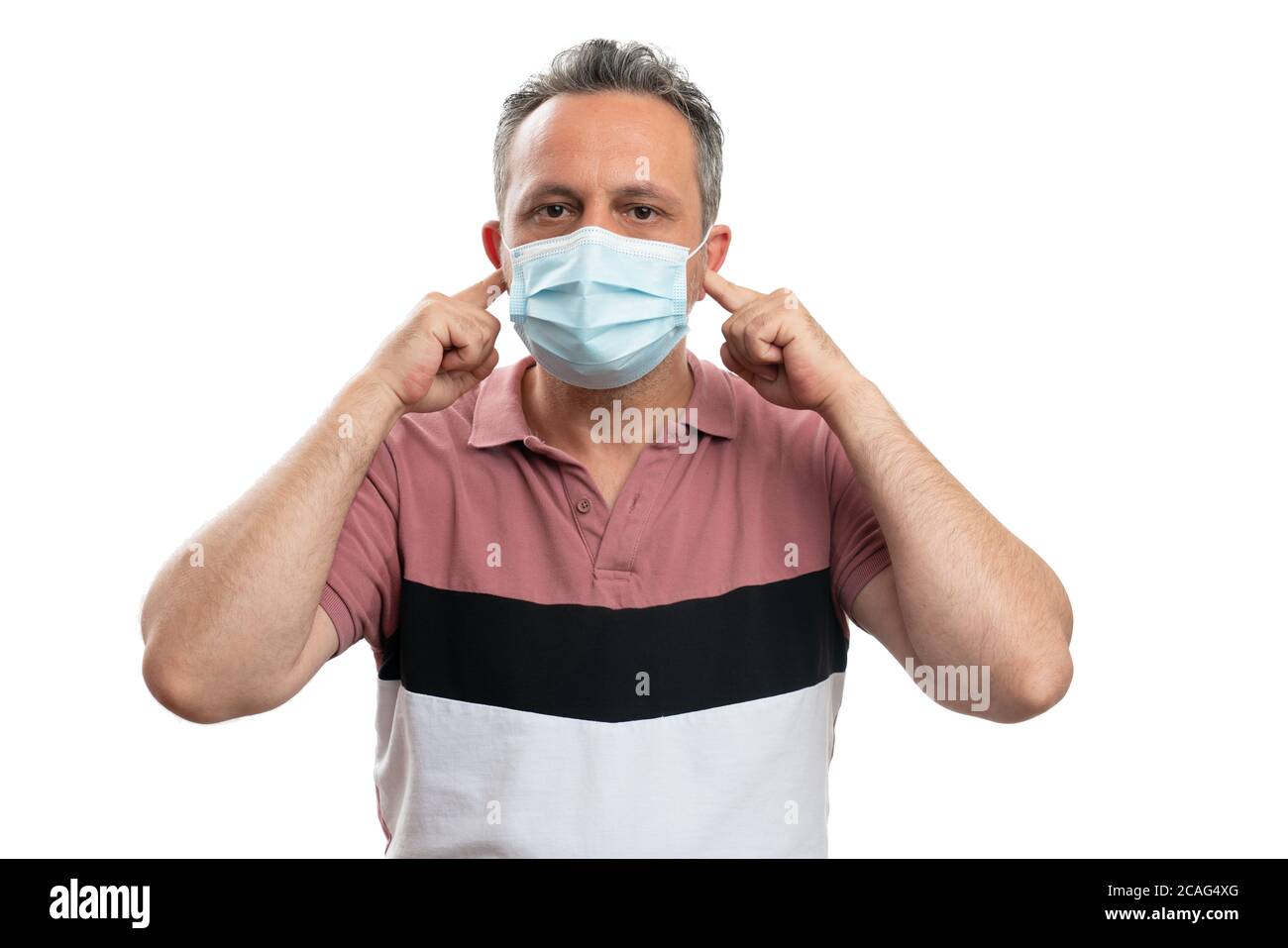 Man having serious expression putting index fingers in ears with medical mask as no hearing gesture covid19 concept isolated on white background Stock Photo