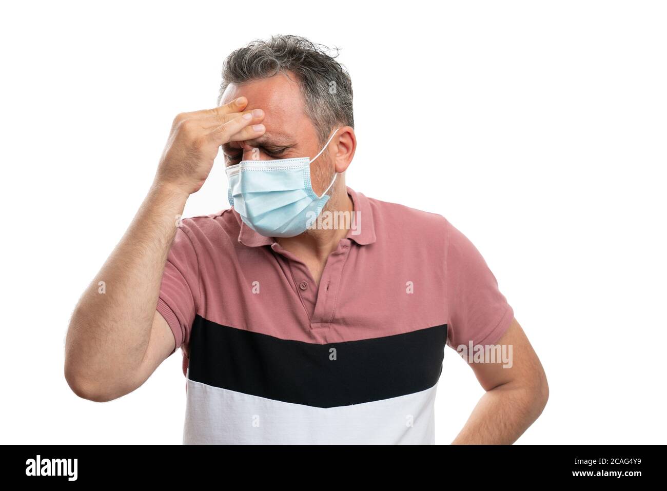 Adult man touching forehead with hand as migraine covid19 flu influenza symptom concept wearing surgical mask isolated on white background Stock Photo