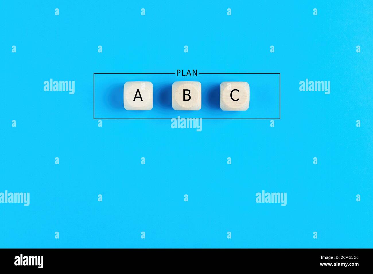 Plan a, b and c on wooden cubes on blue background. Choosing a business strategy plan out of three options. Stock Photo
