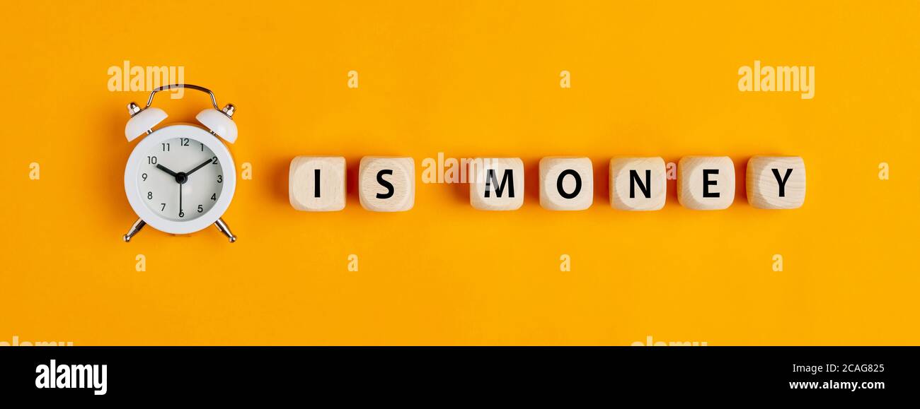 Time is money concept with alarm clock and word written on wooden block ...