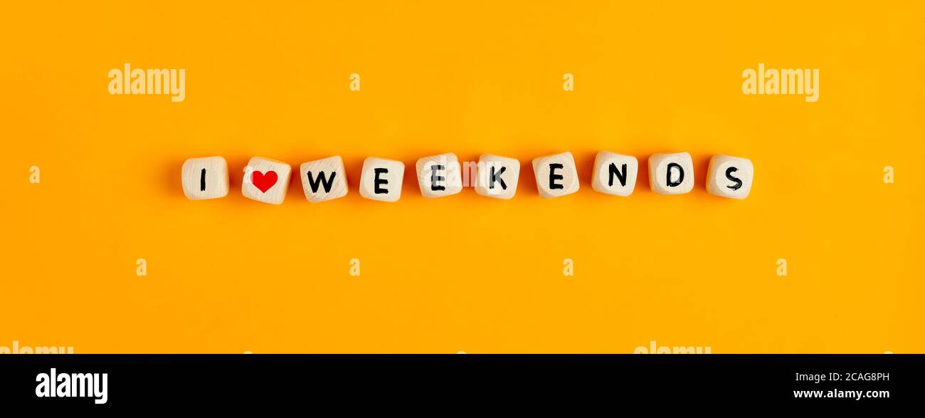 I love weekends text written with heart icon on wooden cubes against yellow background. Weekend concept. Stock Photo