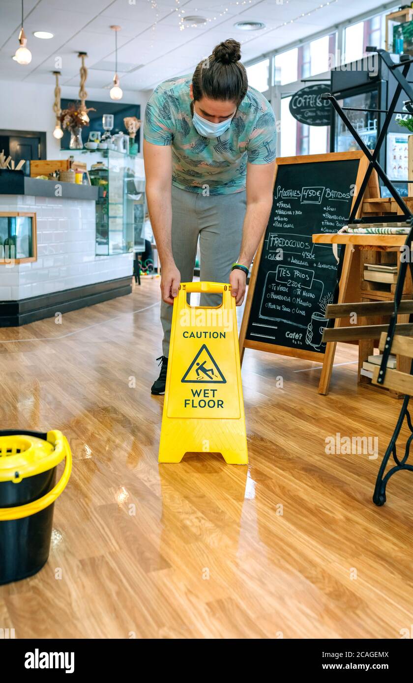 Worker placing wet floor sign after mopping Stock Photo