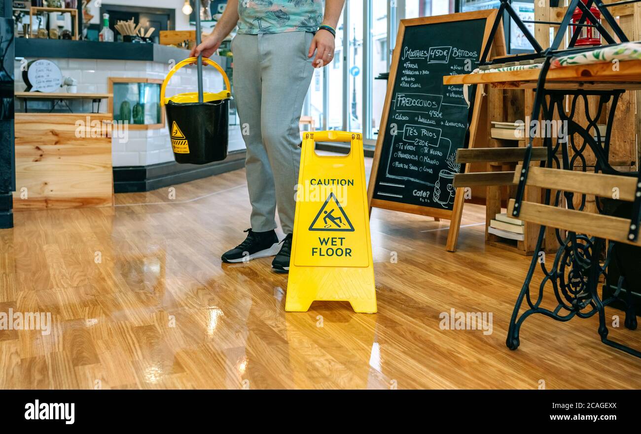 Worker placing wet floor sign after mopping Stock Photo