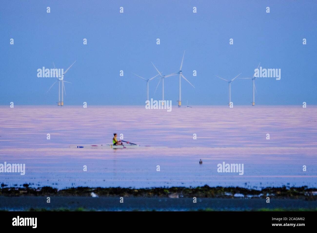 Worthing Beach, Worthing, UK. 6th Aug, 2020. A rower traverses the calm sea as the sun sets casting a warm glow on a warm summer evening. Rampion Wind Farm can be seen in the background, 13km-16km off shore. Picture by Credit: Julie Edwards/Alamy Live News Stock Photo