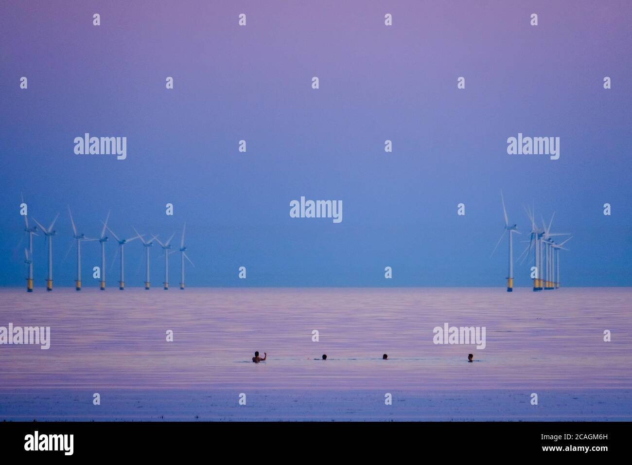 Worthing Beach, Worthing, UK. 6th Aug, 2020. People swim in the calm sea as the sun sets casting a warm glow on a warm summer evening. Rampion Wind Farm can be seen in the background, 13km-16km off shore. Picture by Credit: Julie Edwards/Alamy Live News Stock Photo